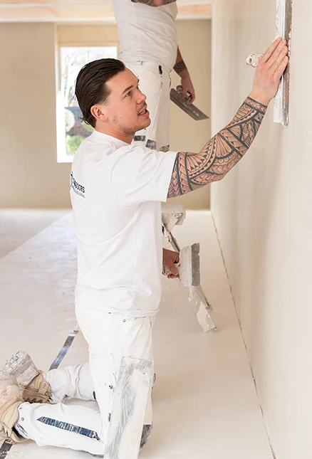 JPB is bezig een muur behangklaar te maken